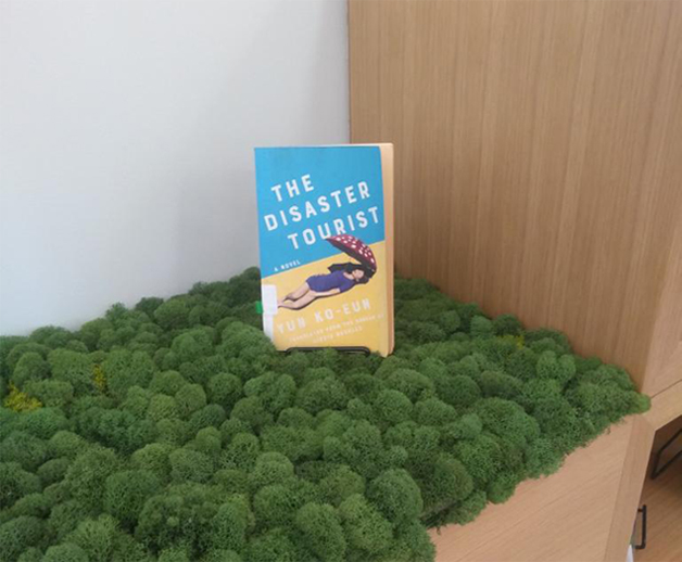The Disaster Tourist on display as a featured book at the Brooklyn Public Library in fall 2023, The Disaster Tourist on display in the English section of a bookstore in Latvia
