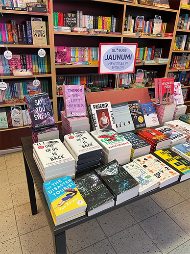 The Disaster Tourist on display as a featured book at the Brooklyn Public Library in fall 2023, The Disaster Tourist on display in the English section of a bookstore in Latvia